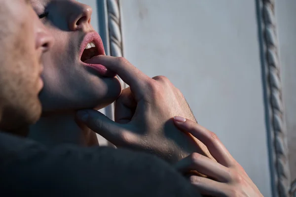 Um homem e uma mulher em um momento íntimo, com o dedo na boca dela.